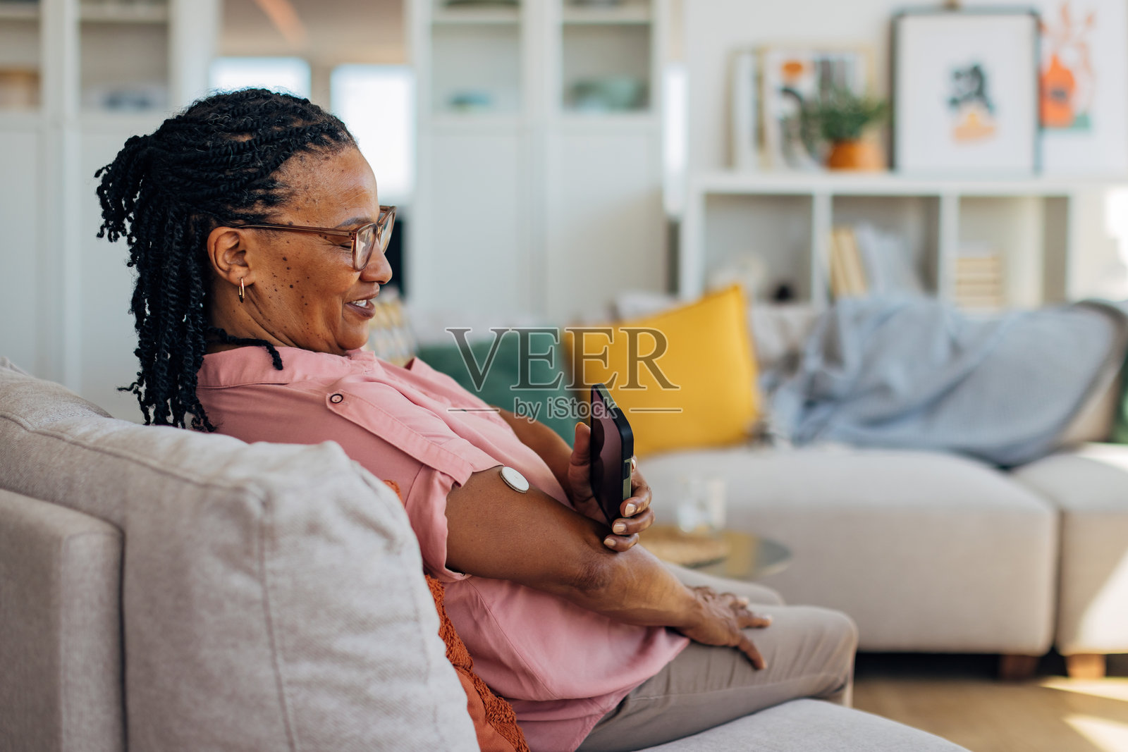 一位年长的黑人女性正在用手机检查她的血糖水平，扫描她上臂上的连续血糖监测仪。照片摄影图片