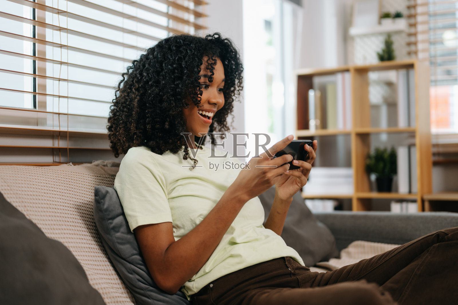 非洲女性在家沙发上使用智能手机和平板电脑照片摄影图片