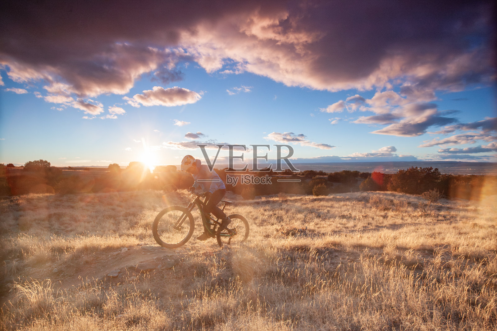 山地自行车手在日出时沿着沙漠小径骑行照片摄影图片