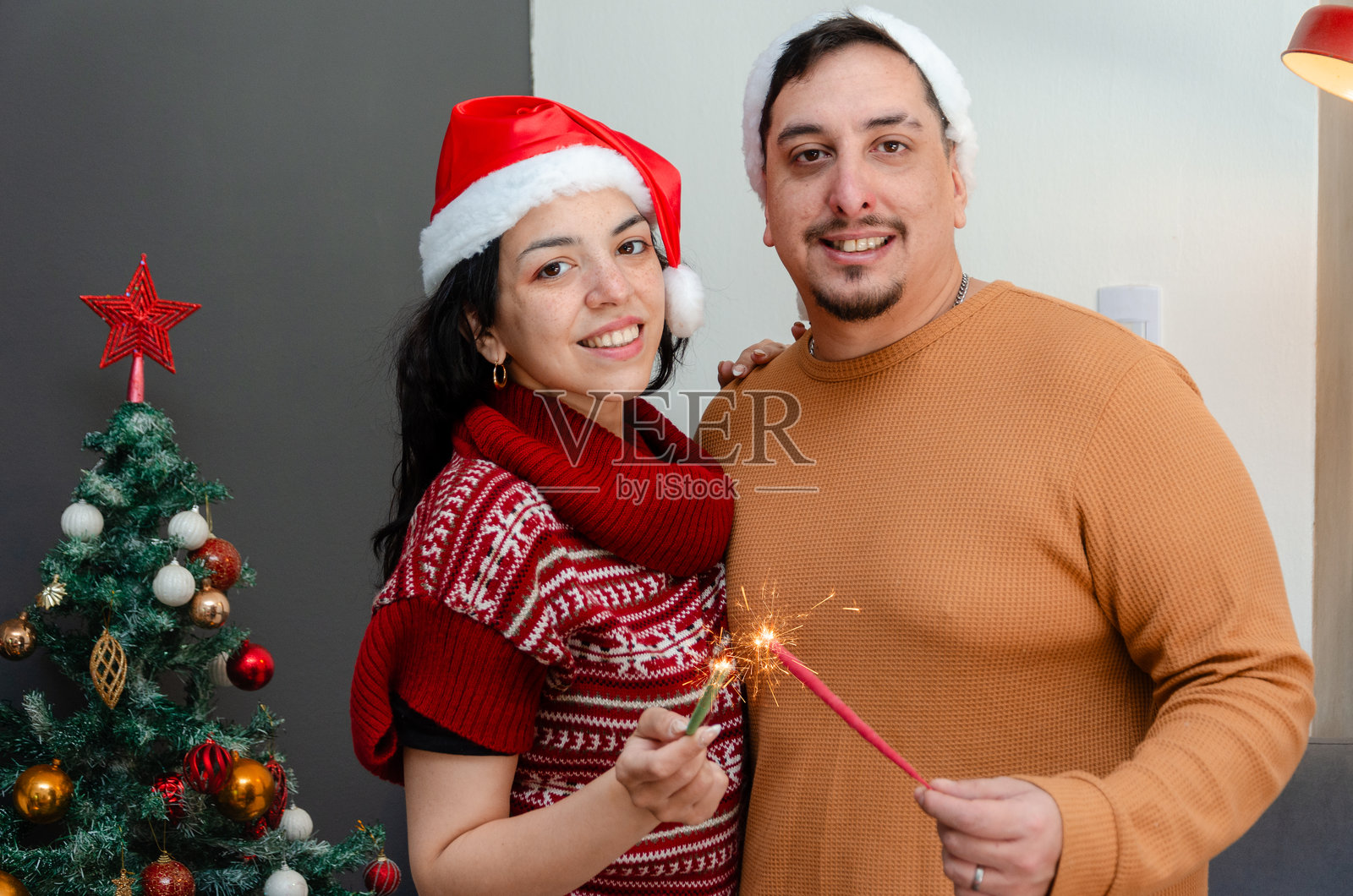 年轻情侣戴着圣诞帽，手持烟花棒照片摄影图片