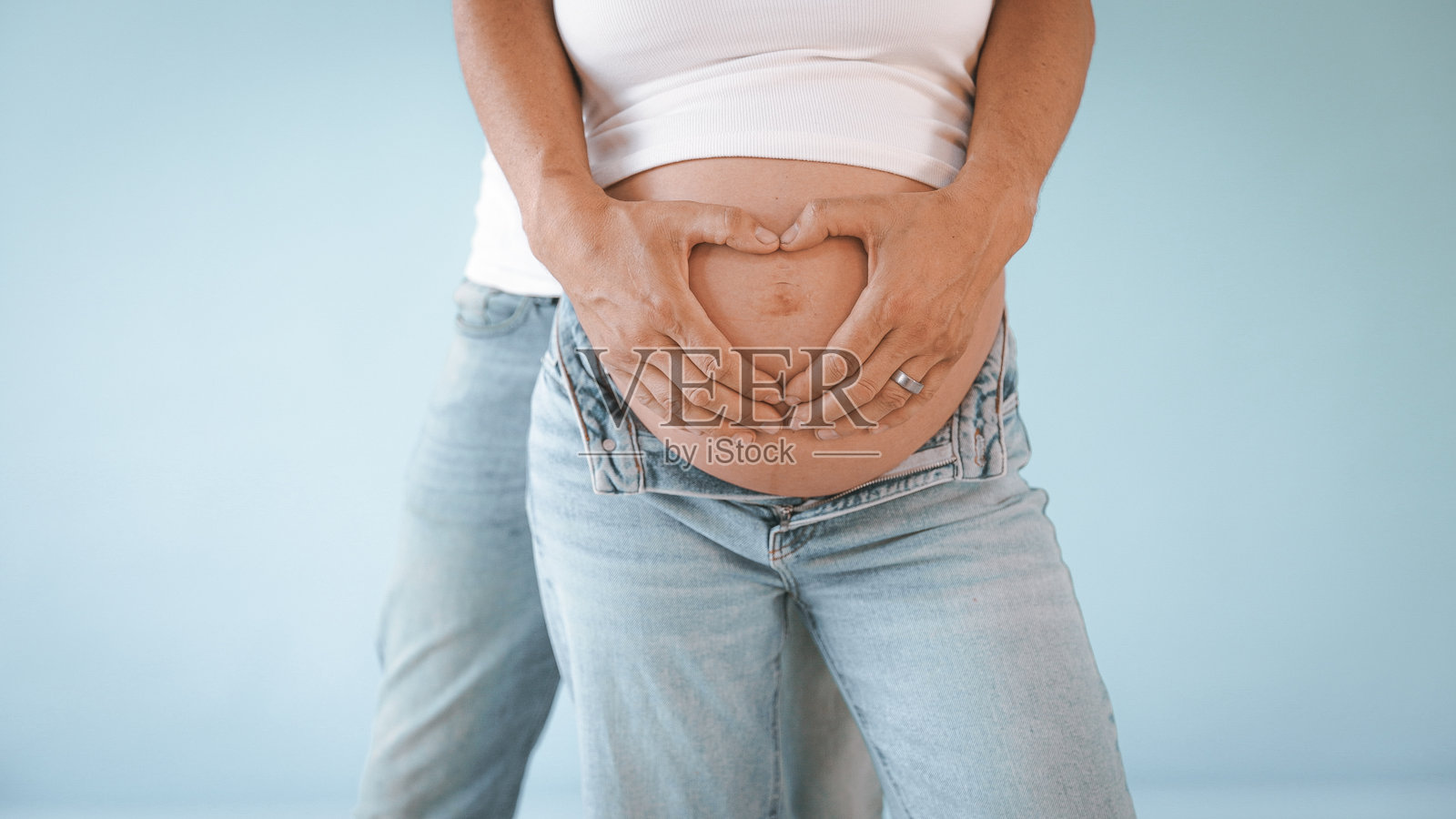 情侣在孕妇肚子上做心形手势照片摄影图片