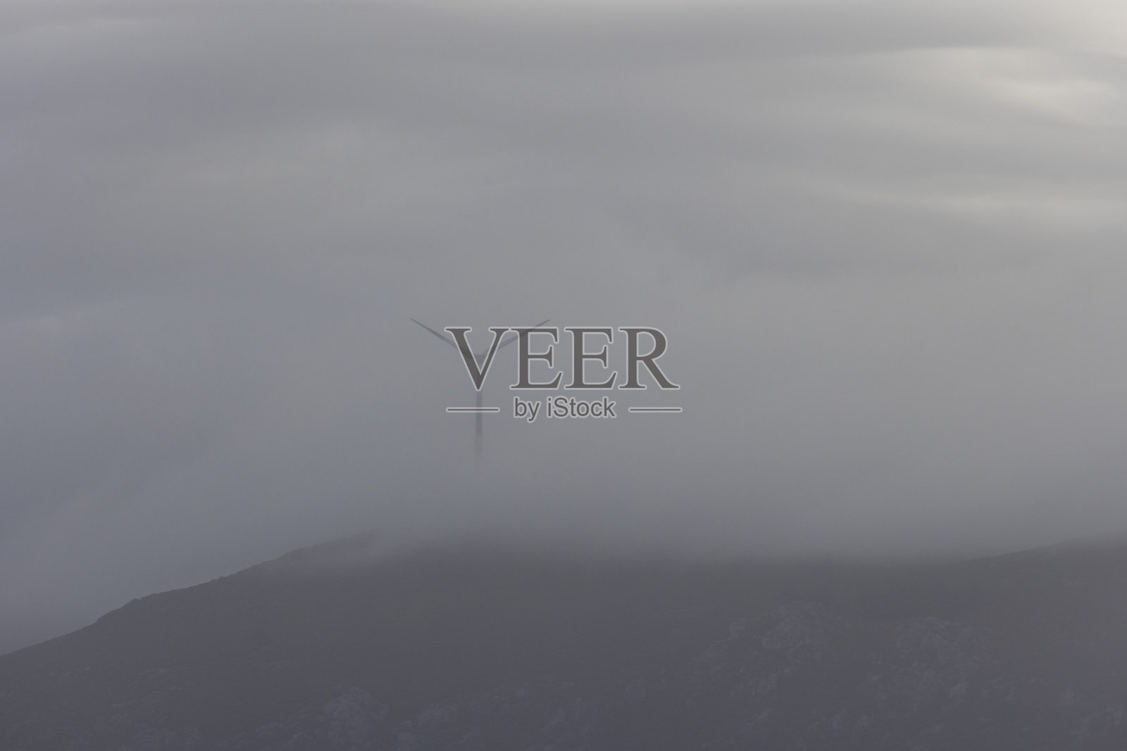 天空中可见一座风力涡轮机，背景模糊。照片摄影图片