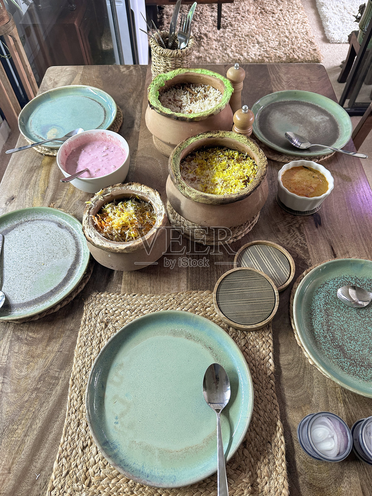 印度外卖晚餐在餐桌上，摆放好的餐具，包含香饭、鸡肉、米饭菜肴、酸奶酱、酸奶、腌菜和调味酱。照片摄影图片