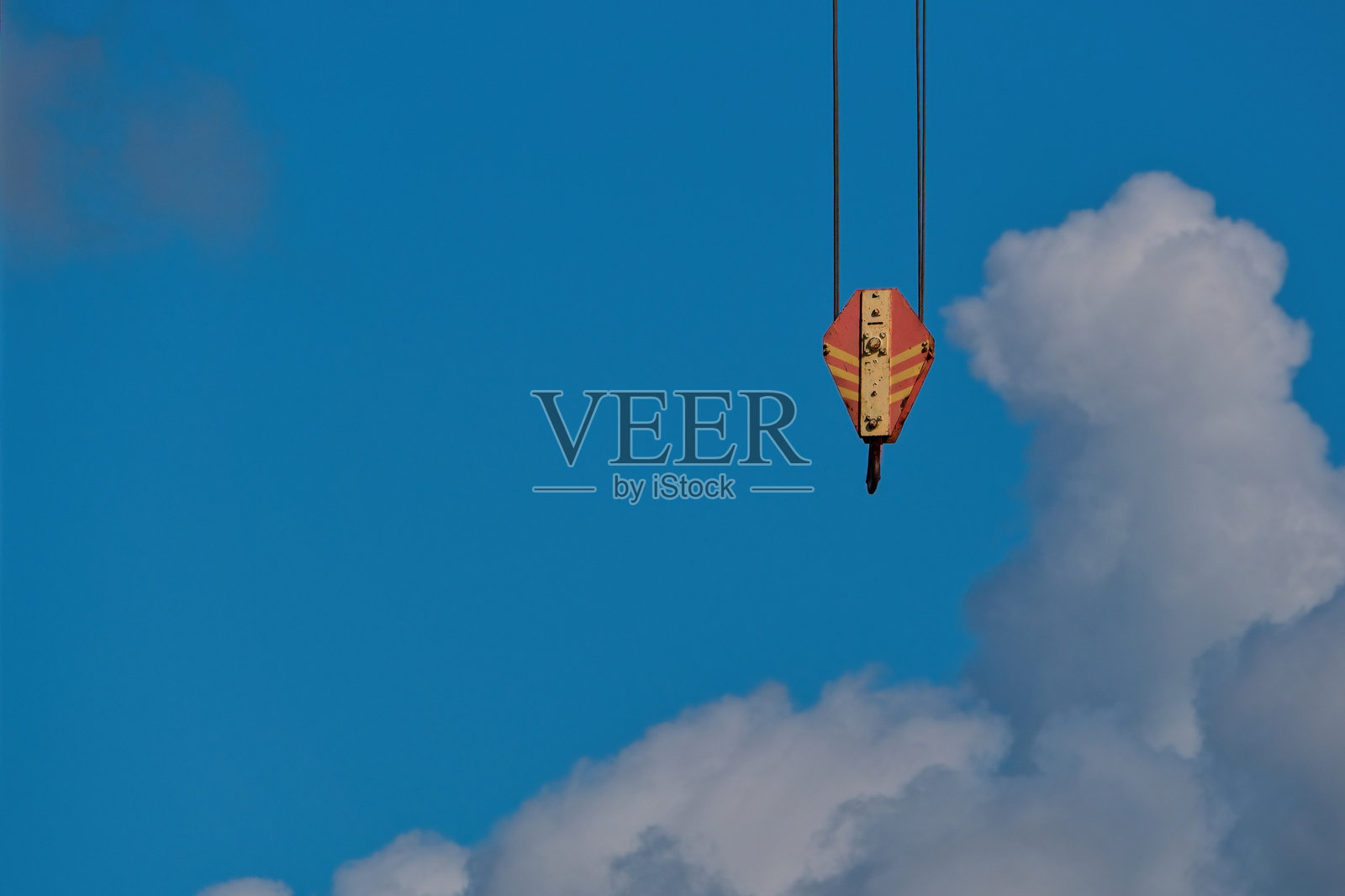 蓝天白云下的建筑起重机钩特写。工业起重设备细节。照片摄影图片