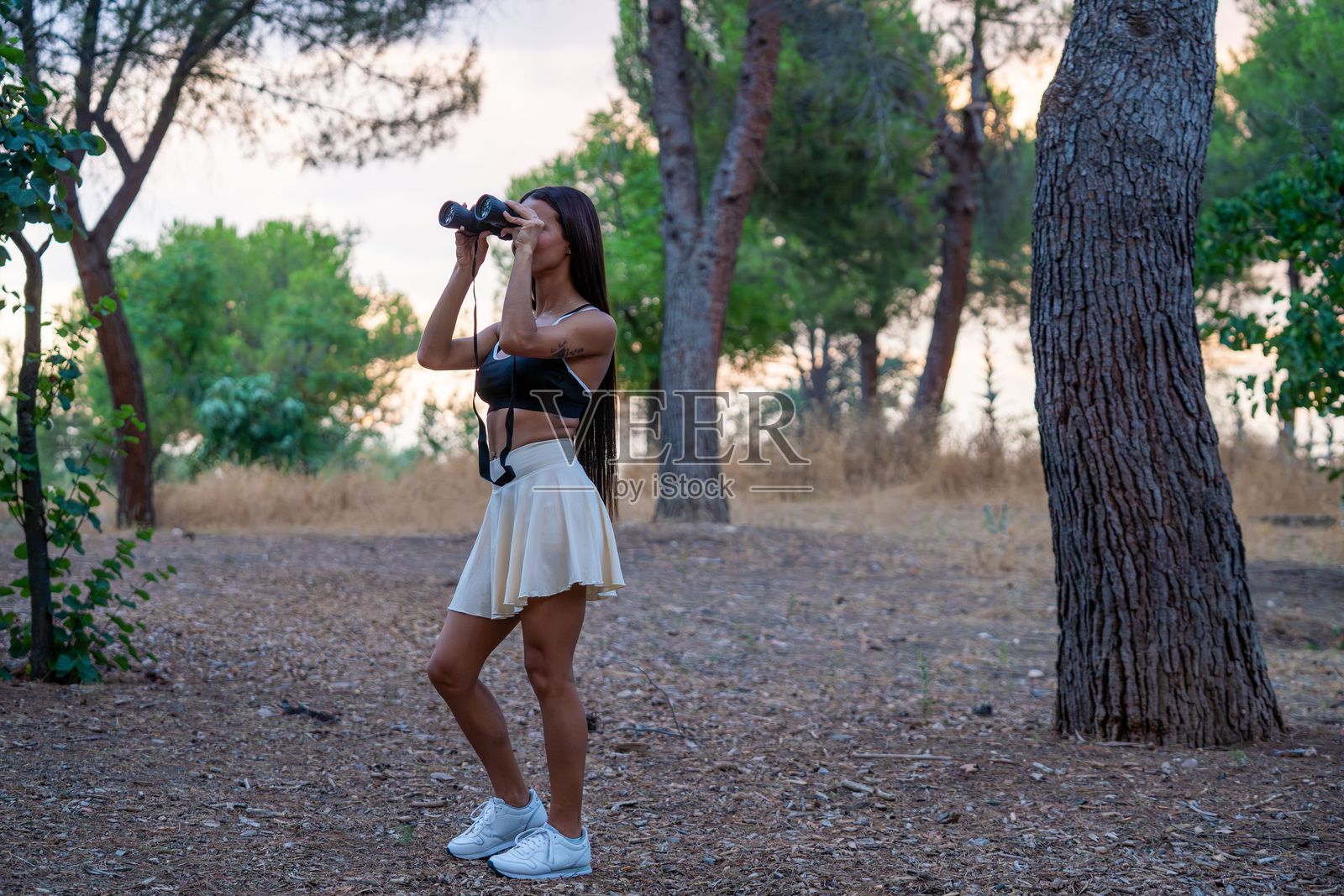年轻女性在森林中使用望远镜照片摄影图片