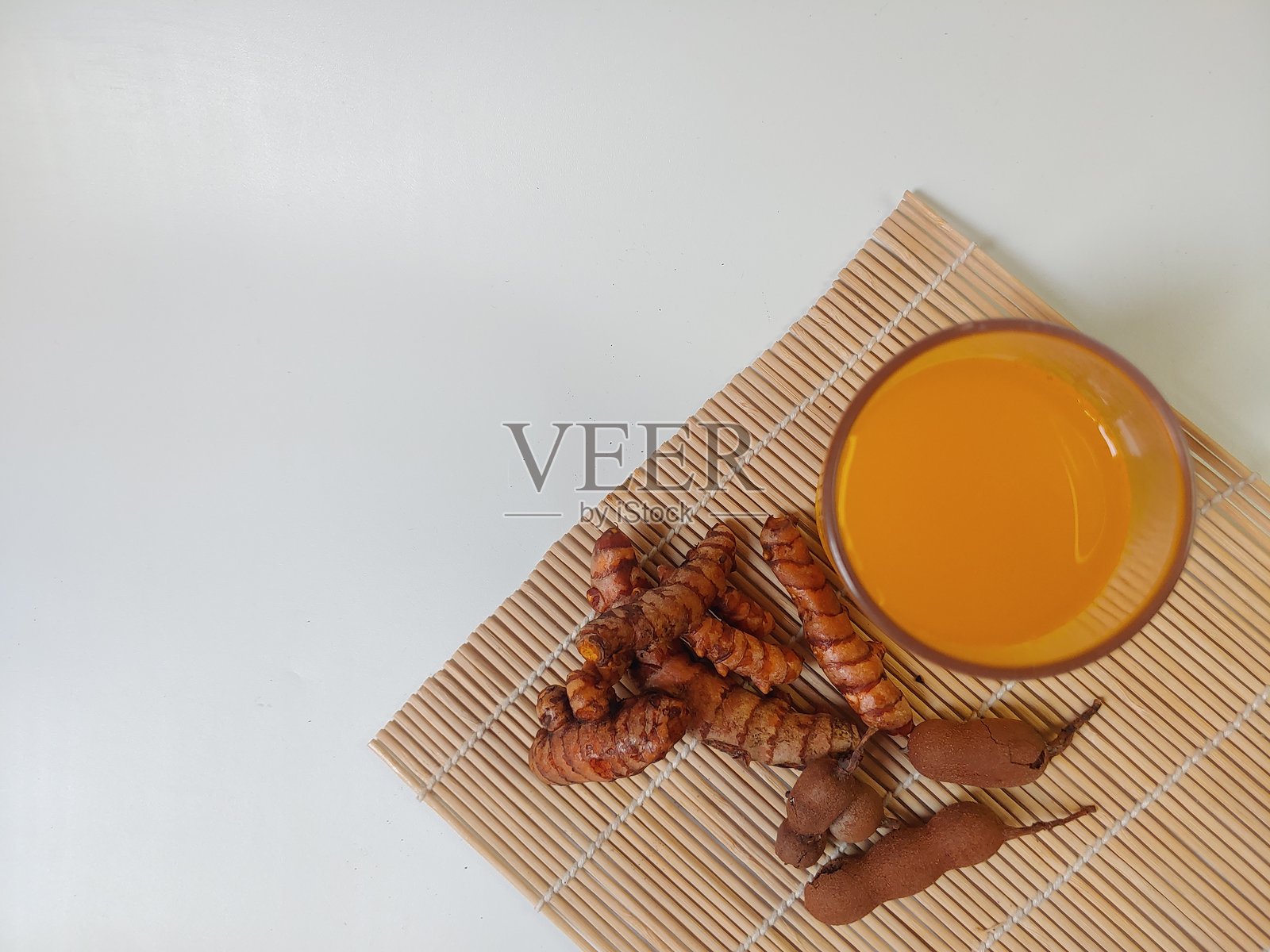 姜母黄姜酸，传统草本饮料，由姜黄和罗望子制成，盛在透明玻璃杯中，背景为白色。照片摄影图片