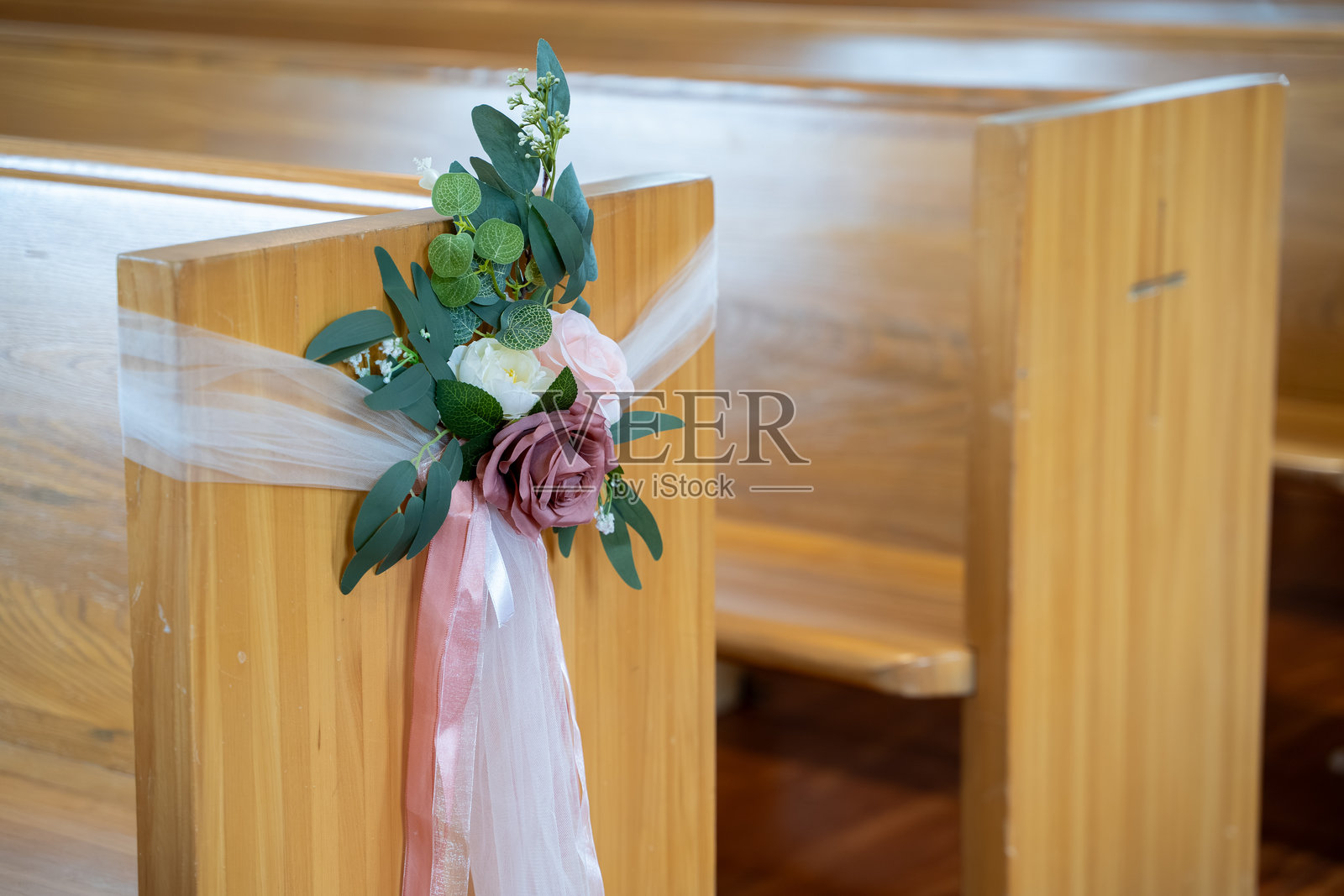 婚礼教堂装饰，木长椅上的花卉布置和丝带。照片摄影图片
