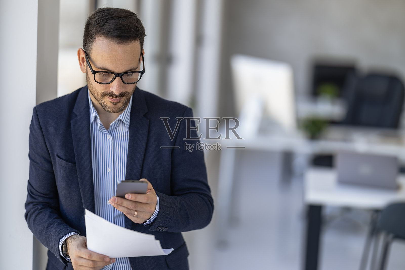 商务专业人士在现代办公空间中分析文件，同时使用智能手机。照片摄影图片