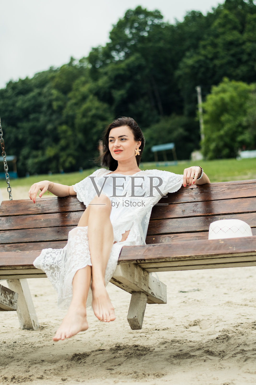 一位拥有奢华黑发的年轻女士坐在海边的秋千上照片摄影图片