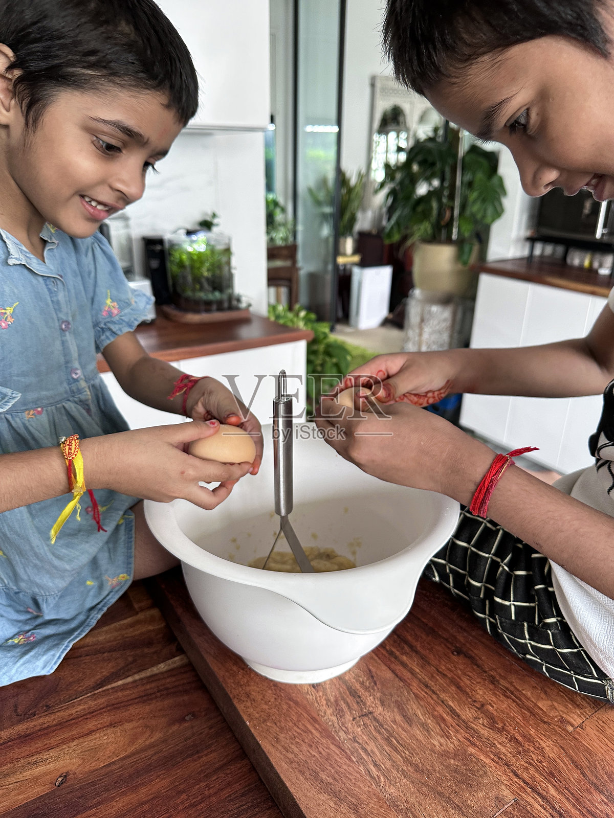 孩子们在厨房里烘焙，正在用打蛋器和搅拌碗混合香蕉面包的蛋糕糊，里面有巧克力和坚果。照片摄影图片