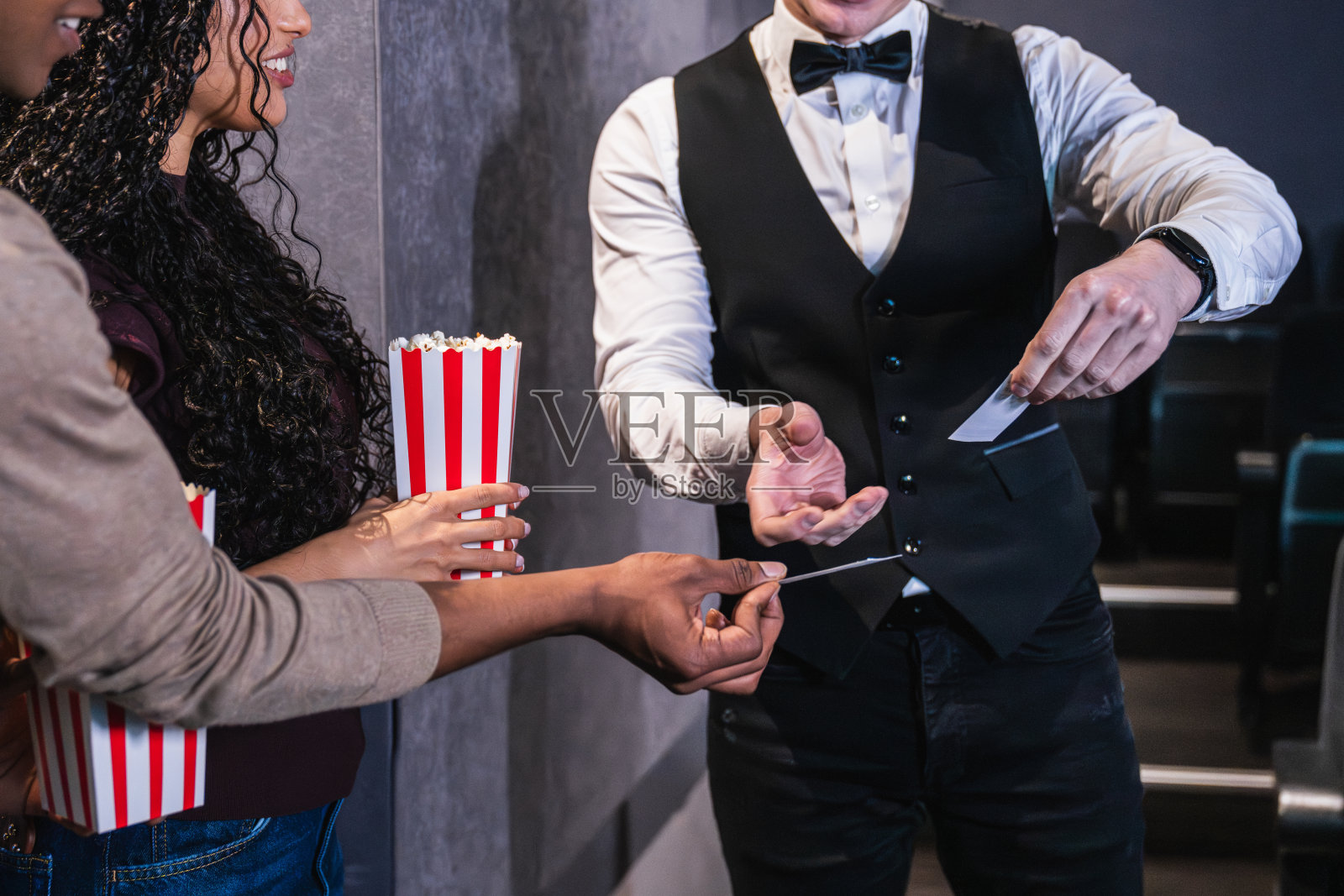 引导员在检查一对情侣进入电影院的票务照片摄影图片