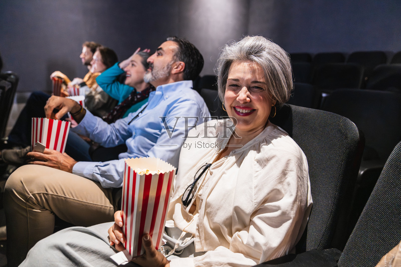 一群人在电影院观看电影并吃爆米花照片摄影图片