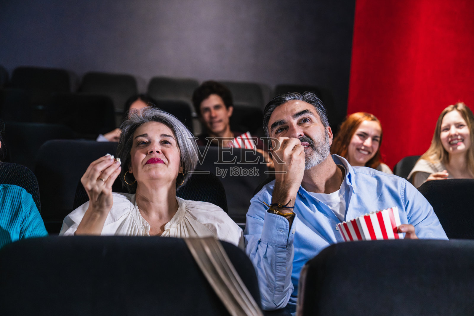 人们在电影院里享受观看电影和吃爆米花的时光照片摄影图片