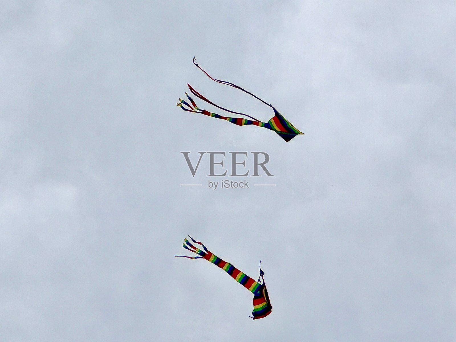 两只多彩的风筝在多云的天空中飞翔照片摄影图片