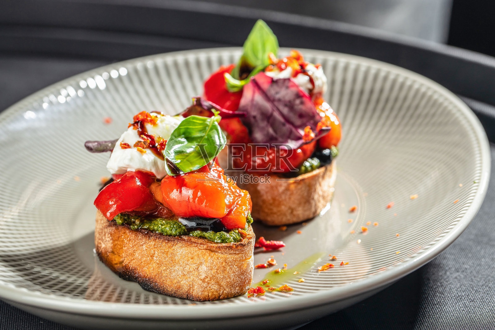 放在陶瓷盘上的烤蔬菜、香蒜酱和奶油奶酪的意式面包。留白空间。照片摄影图片