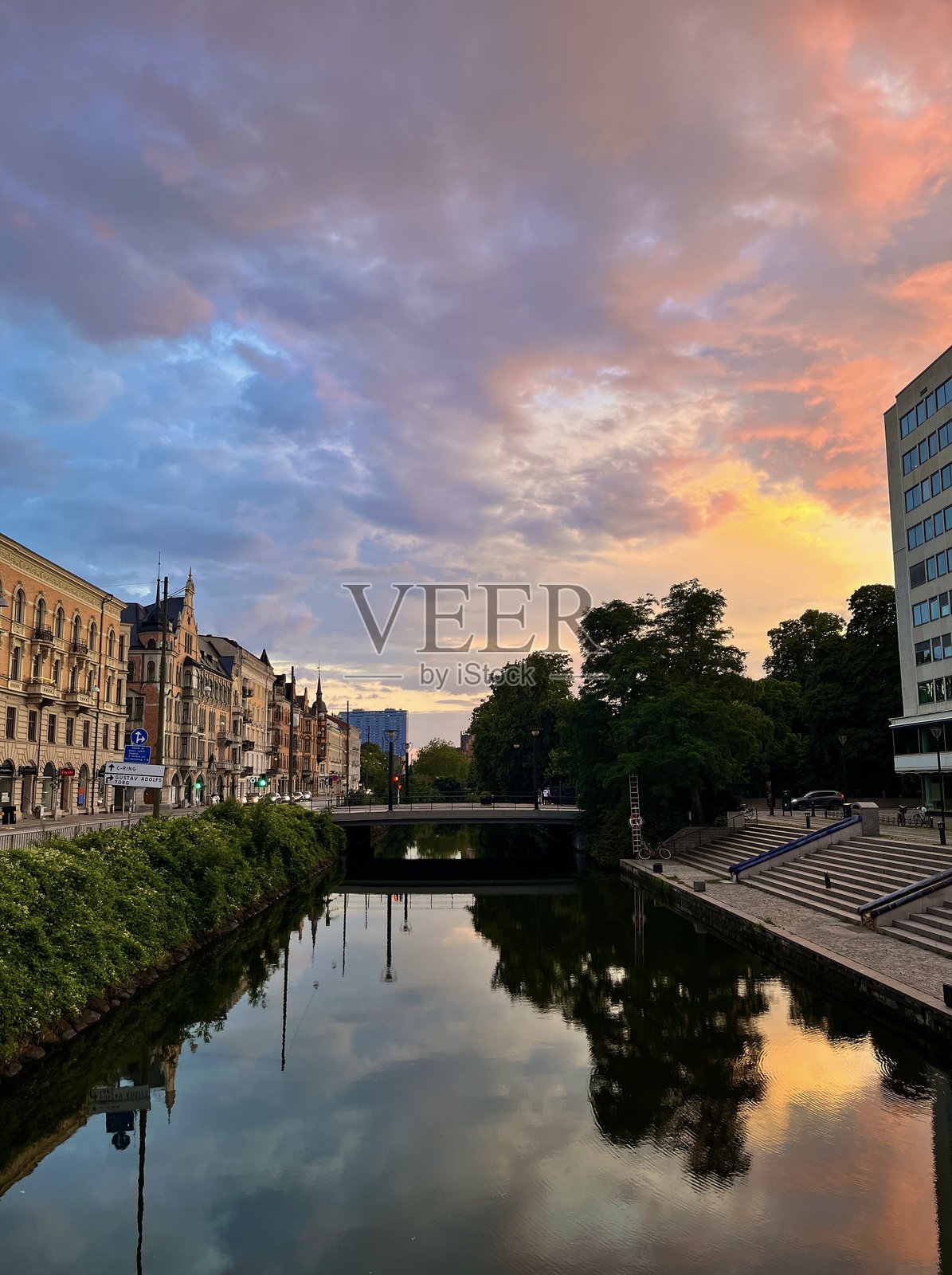 色彩斑斓的日落天空映衬着历史悠久的河边建筑和桥梁照片摄影图片