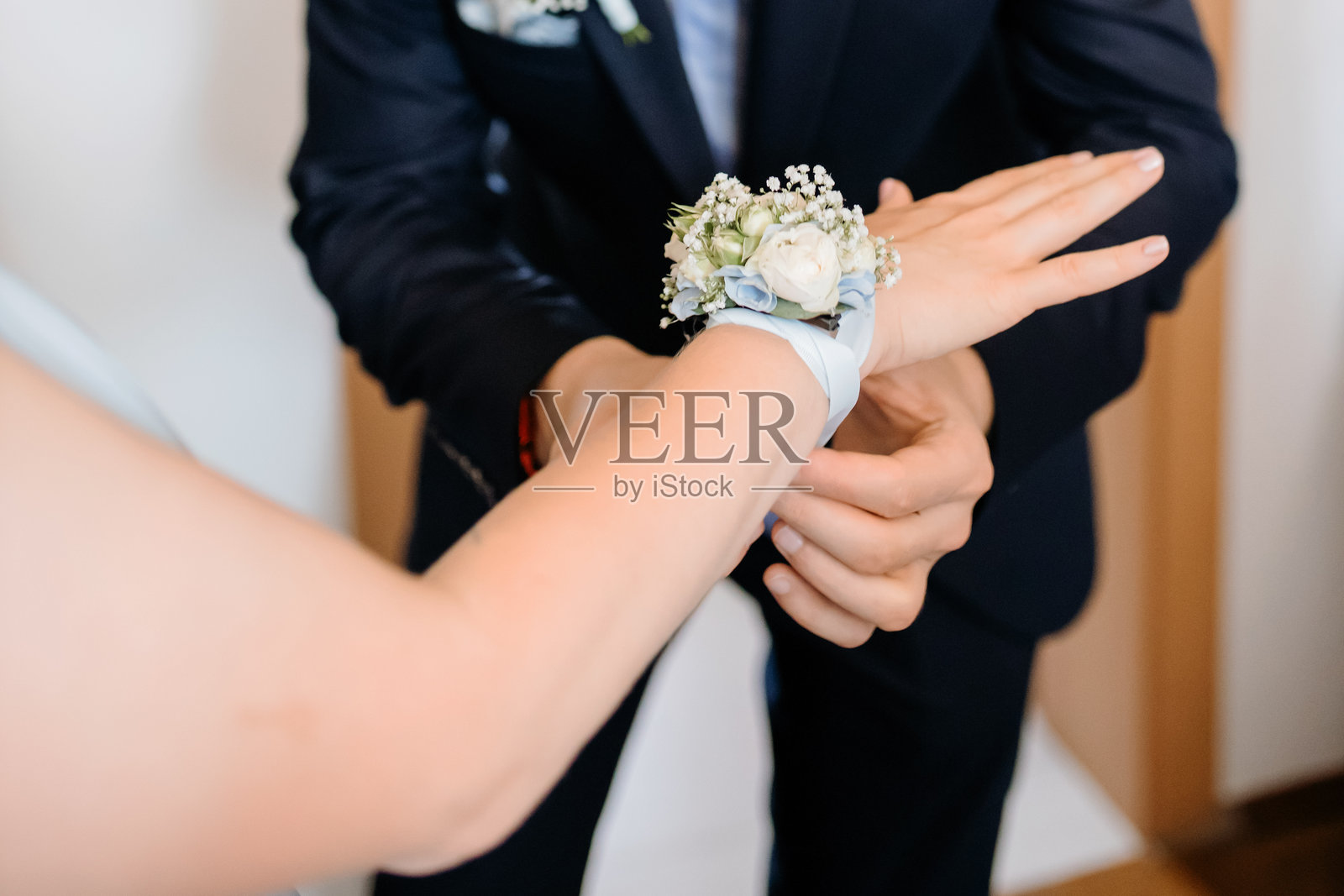 优雅的花卉手腕花束在婚礼准备期间被系在女性手上的特写，象征着庆祝、优雅和传统。照片摄影图片