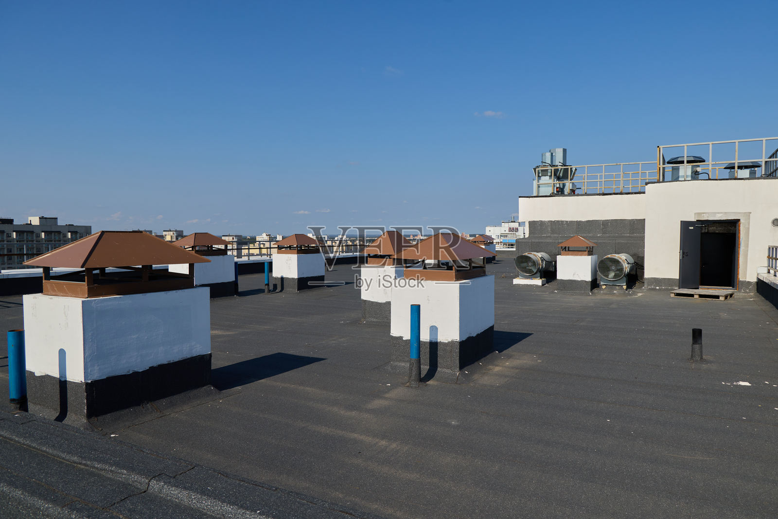 一个充满活力的城市屋顶展示了通风结构，背景是晴朗的蓝天。照片摄影图片