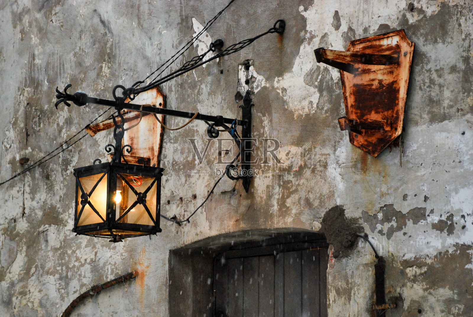 复古铁灯笼悬挂在剥落油漆的风化乡村墙壁上照片摄影图片