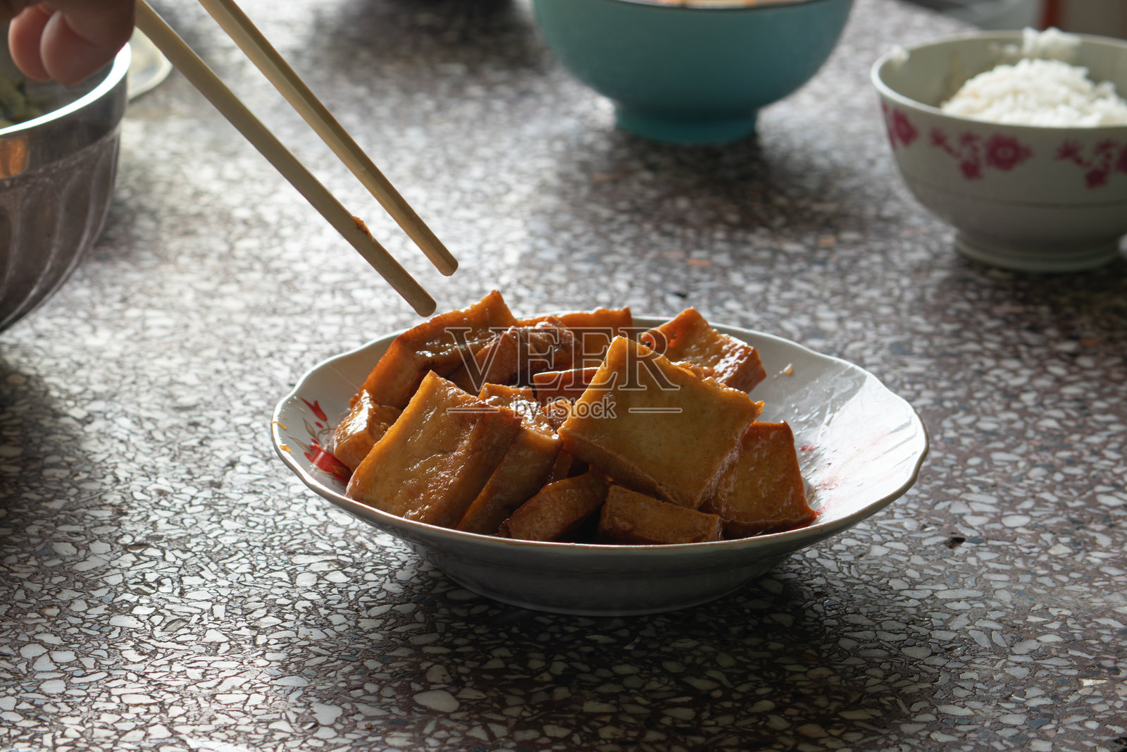 一个人的手用筷子吃传统越南菜炸豆腐，代表亚洲饮食文化和自制餐点。照片摄影图片