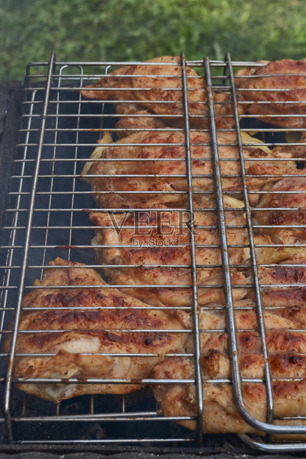 在炭火上烤制的金黄色外壳鸡肉块。照片摄影图片