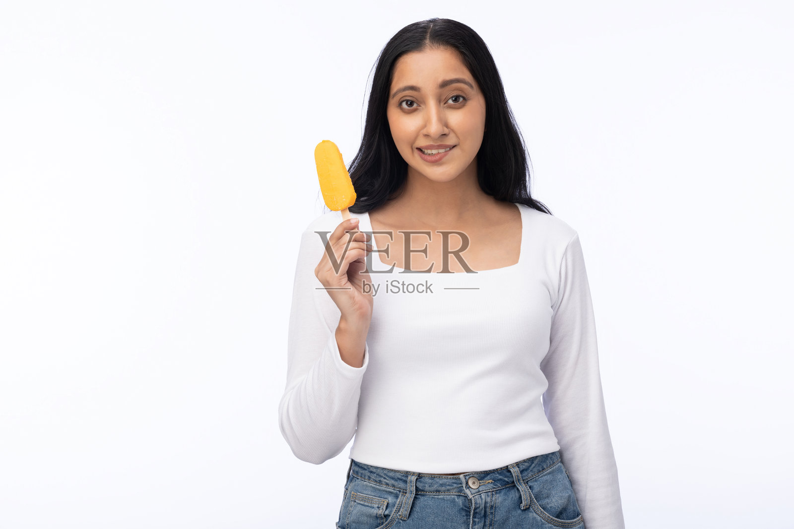 年轻女性穿着现代服装，享用芒果冰淇淋的肖像，背景为白色。照片摄影图片