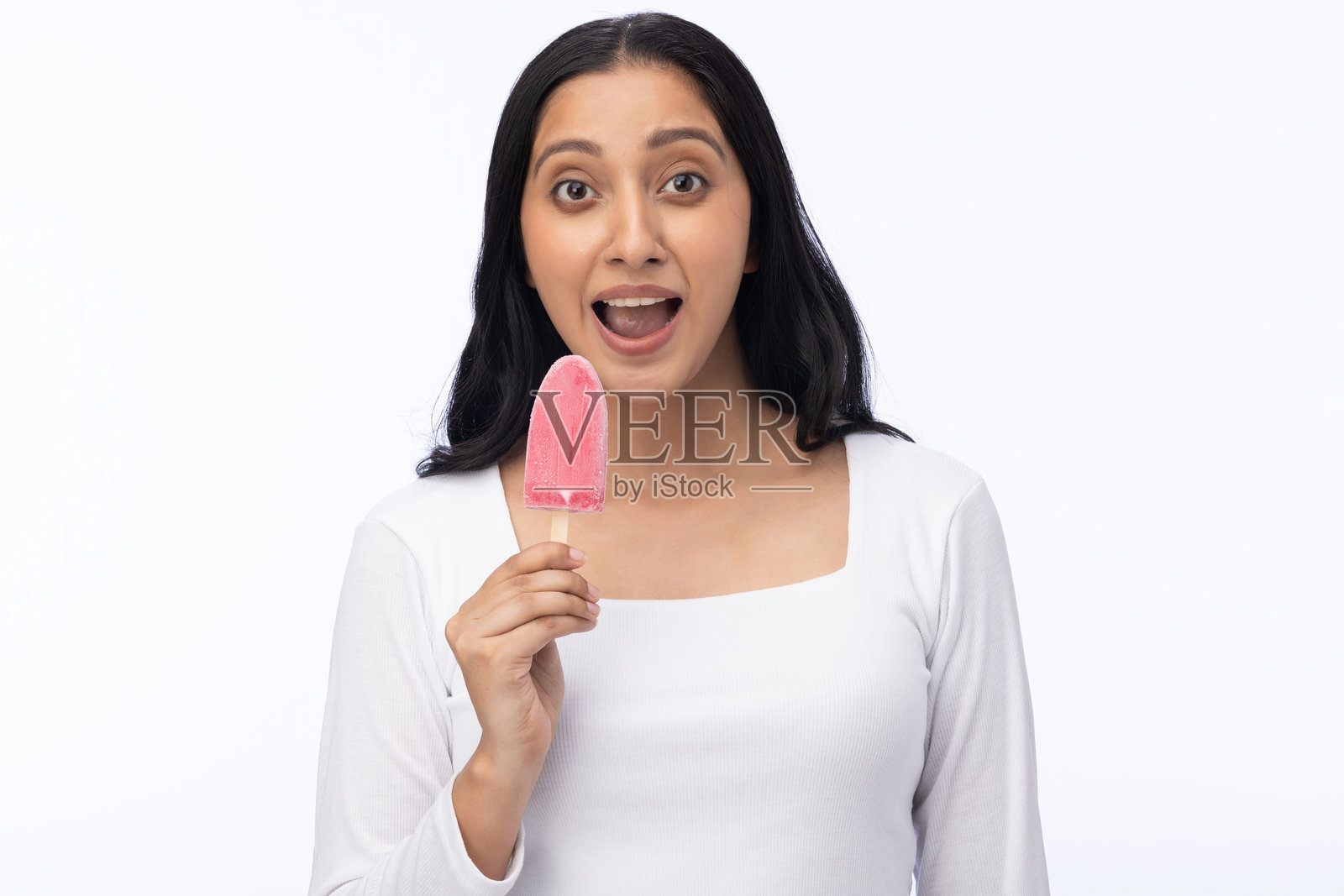 年轻女性穿着现代服装，享用草莓冰淇淋的肖像，背景为白色。照片摄影图片