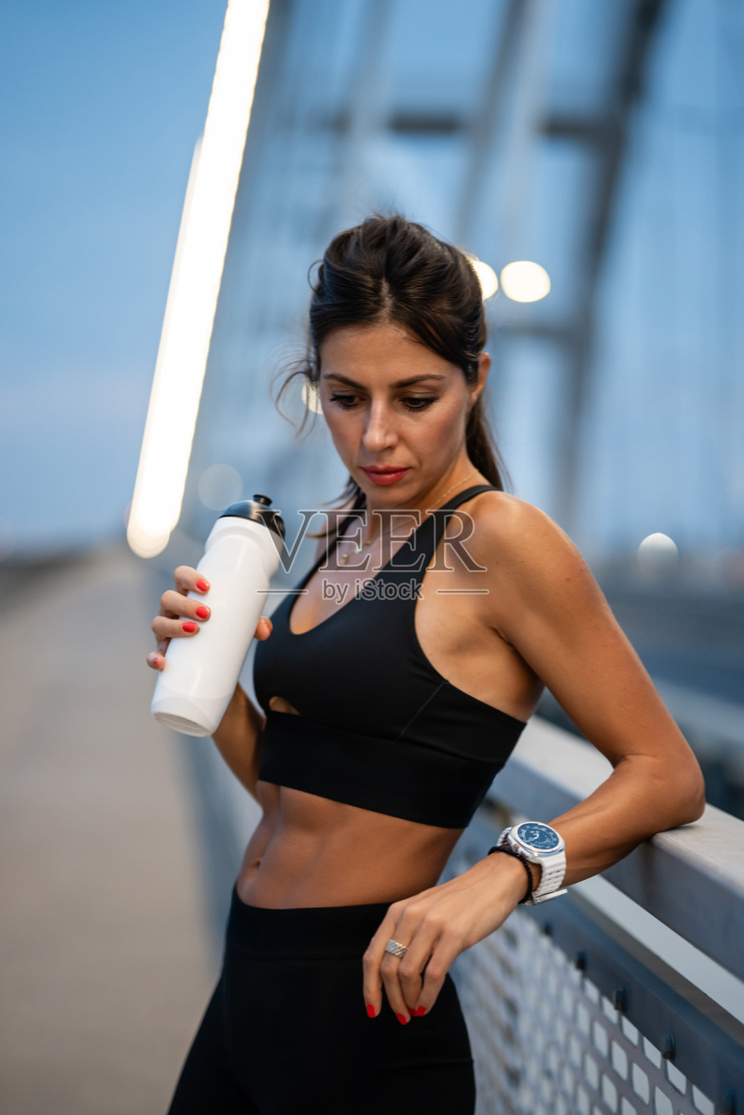 运动女性在桥上训练后喝水照片摄影图片