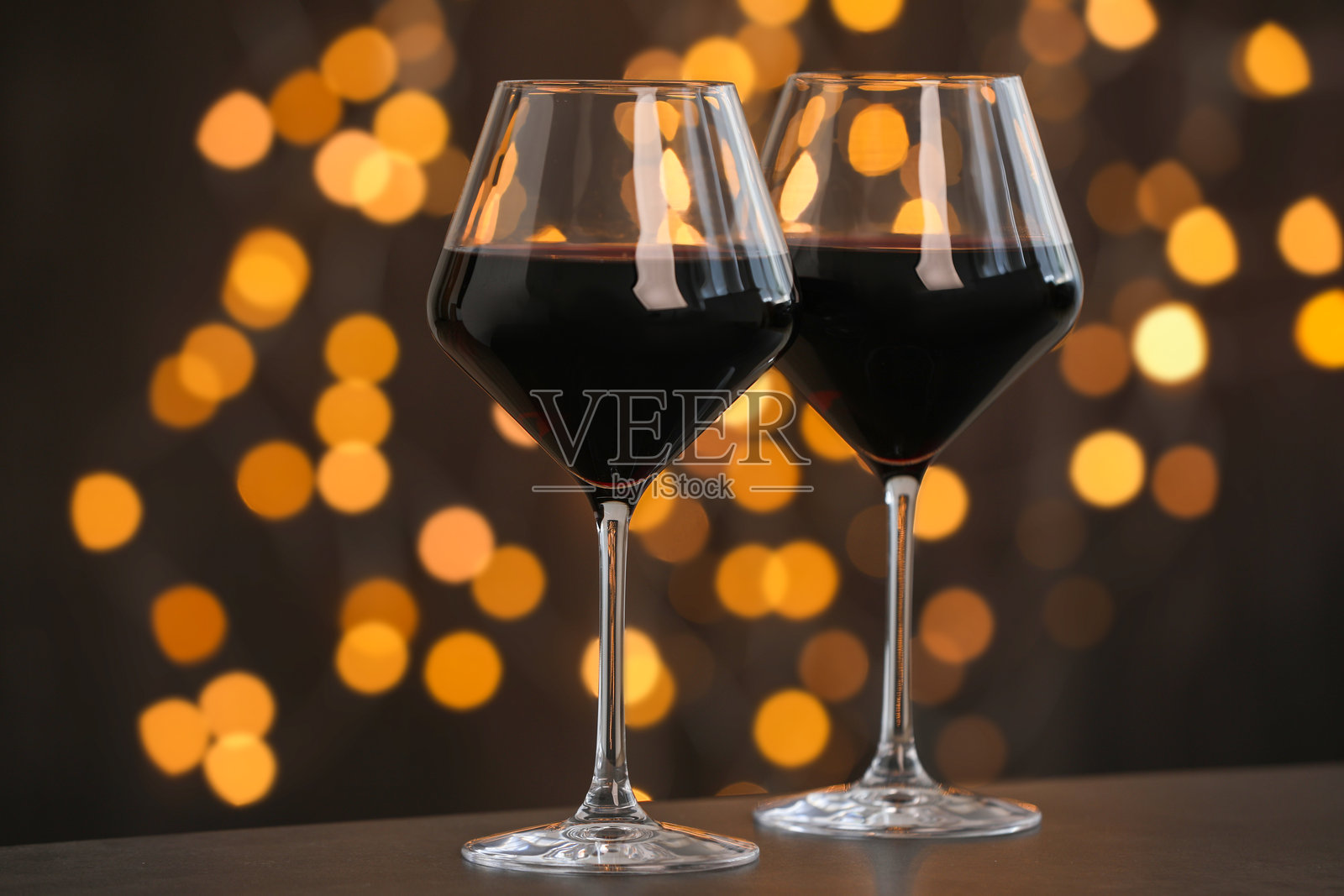 美味的红酒在桌子上的酒杯中，背景昏暗，模糊的灯光，散景效果。照片摄影图片