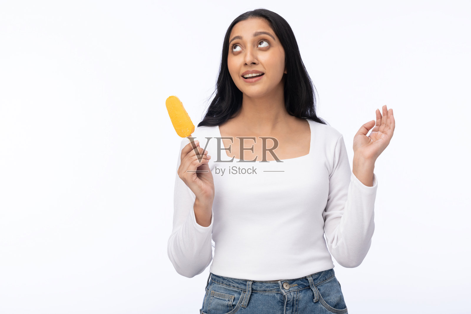 年轻女性穿着现代服装，享用芒果冰淇淋的肖像，背景为白色。照片摄影图片