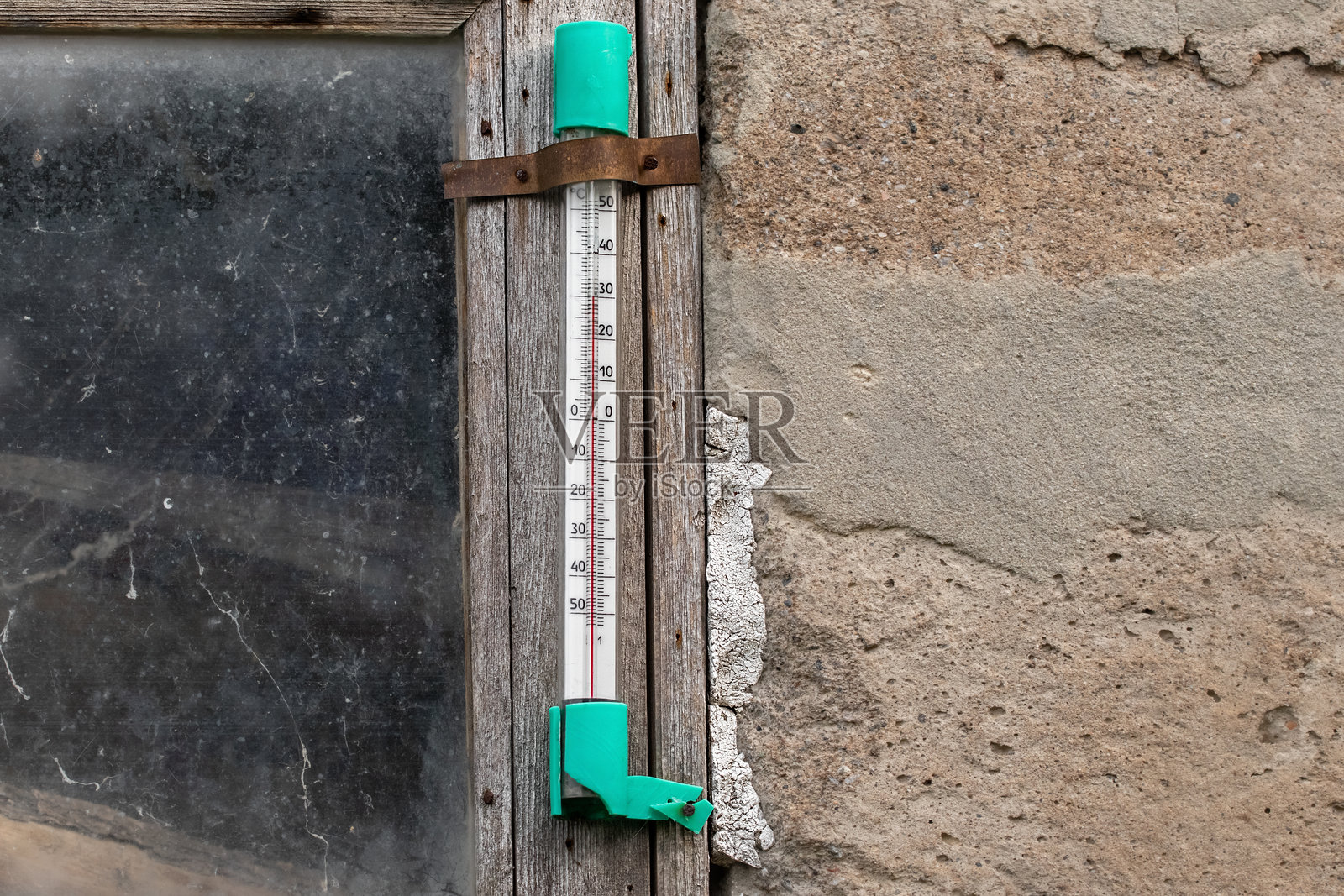 破旧房屋窗户上的街道温度计。温度计显示外面的炎热夏季气温，30摄氏度。照片摄影图片