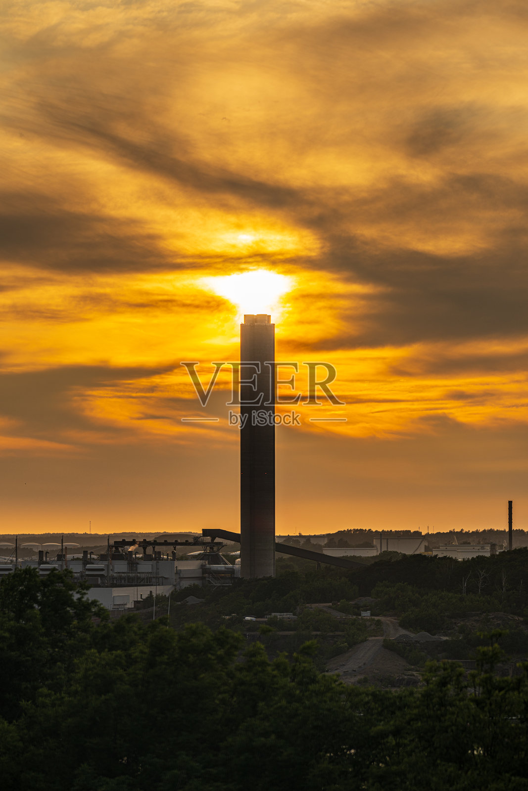 工业烟囱在金色日落下的剪影。照片摄影图片
