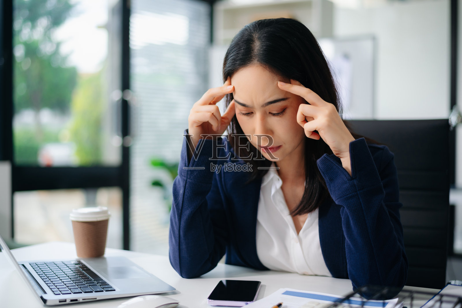 亚洲女商人在办公室桌前展示压力和沮丧，旁边有笔记本电脑和计算器。真实的人，财务压力，工作过载，截止日期压力，职业倦怠概念。照片摄影图片