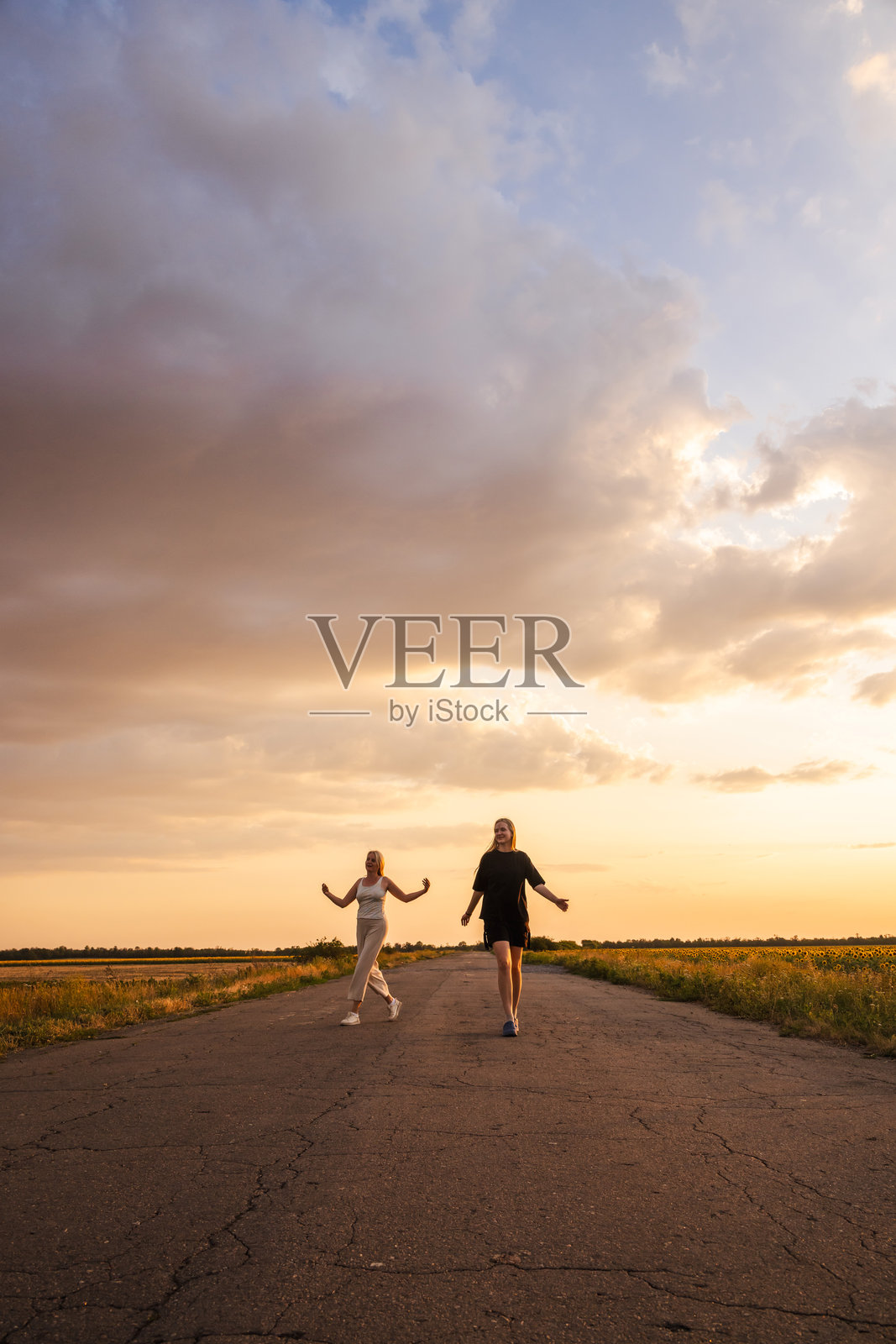 两位女性在乡间小路上散步，微笑着享受黄昏的户外时光照片摄影图片