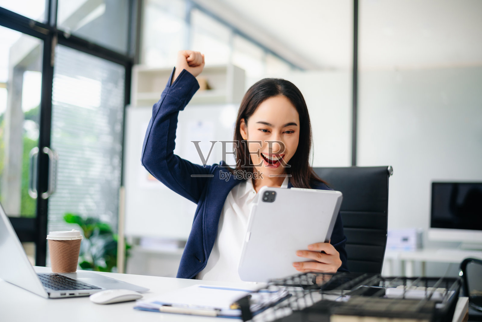 亚洲女商人在办公室桌前举起拳头庆祝成功照片摄影图片