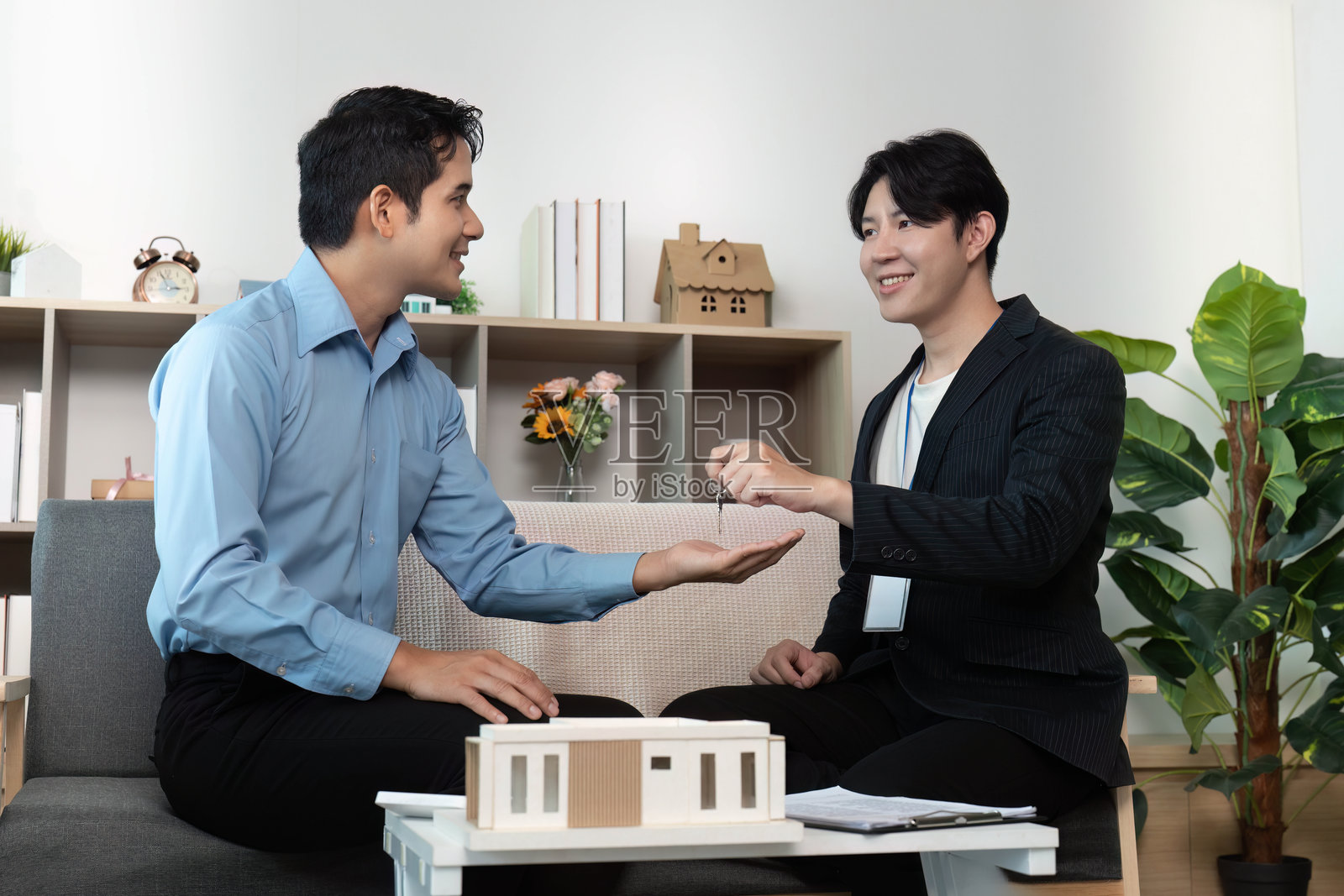 房地产交易。经纪人在现代环境中将钥匙交给客户。照片摄影图片