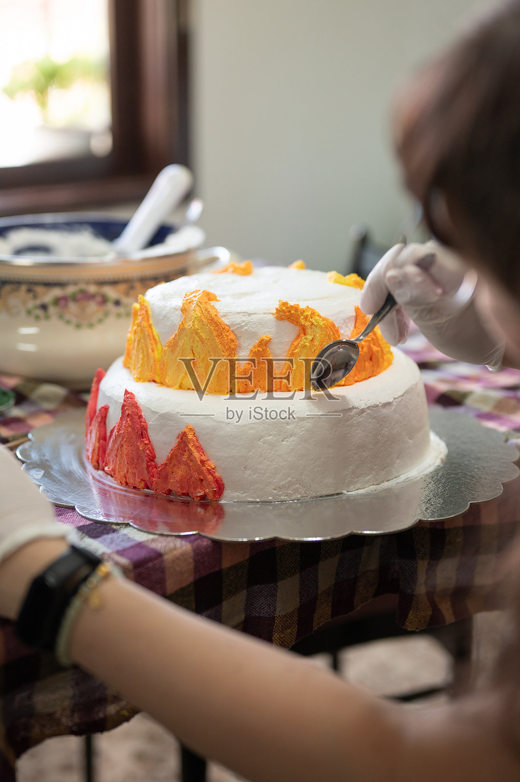 创意烘焙师在色彩缤纷的火焰主题蛋糕上切割翻糖火焰照片摄影图片