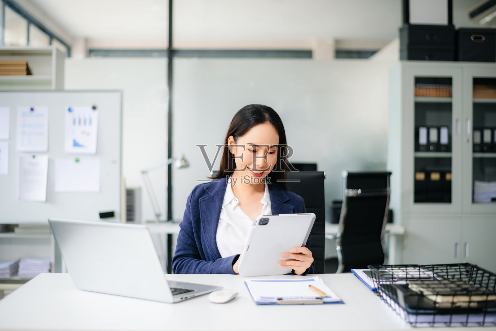自信的亚洲女商人在现代办公室工作，使用笔记本电脑和平板电脑，在桌子上制定战略照片摄影图片