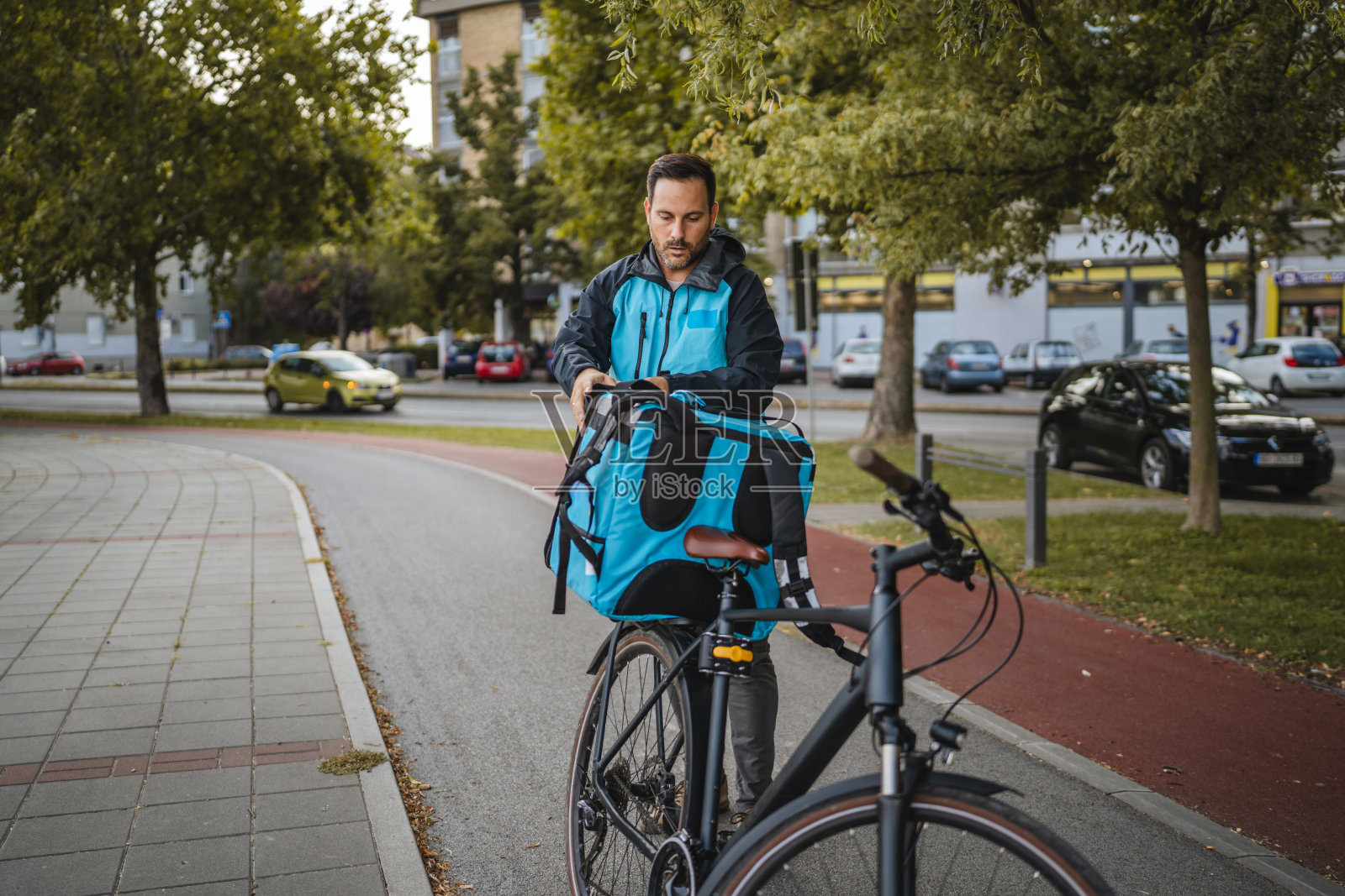 送餐员在城市环境中将食品袋固定在自行车上照片摄影图片
