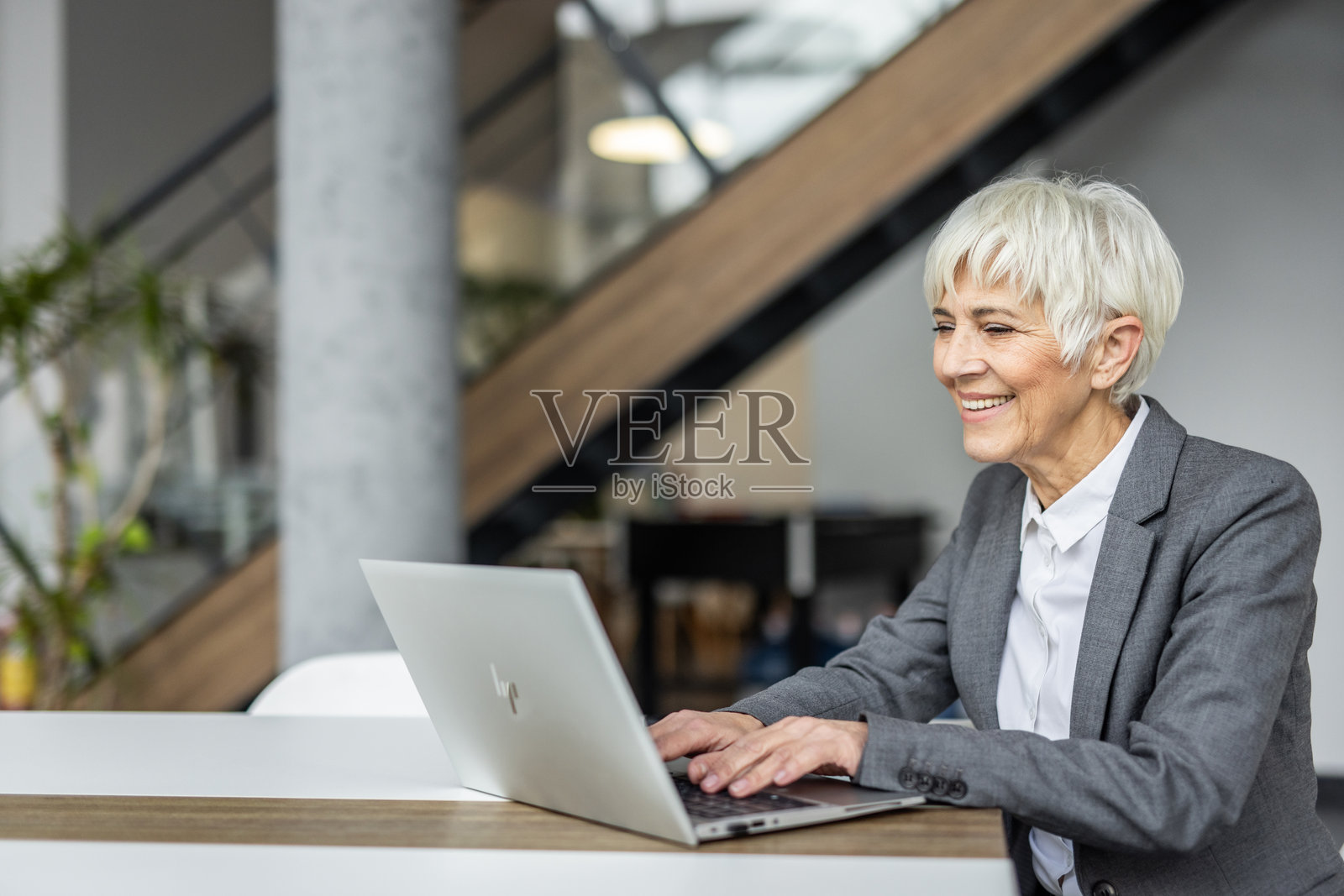 在现代办公室里工作的资深女商人使用笔记本电脑照片摄影图片