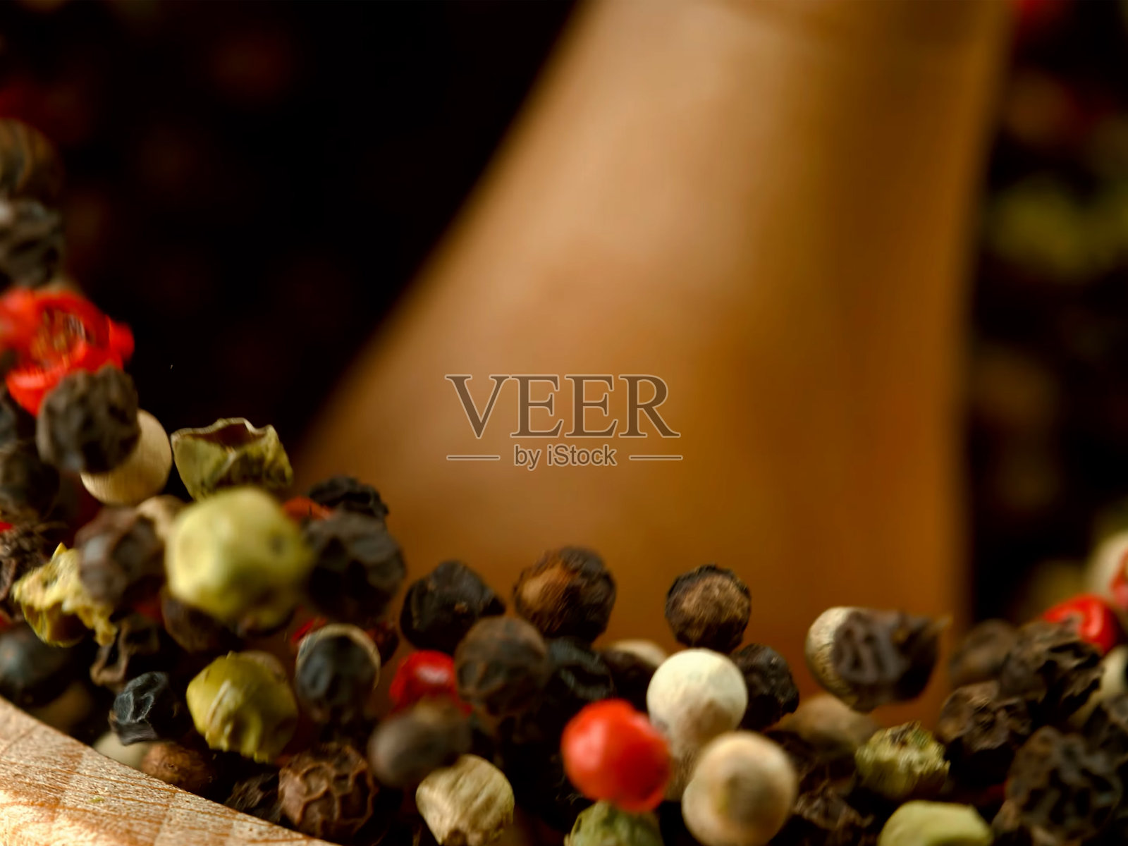 用研钵和杵手工研磨红、黑、白胡椒等香料，特写宏观镜头，香料飞溅。照片摄影图片