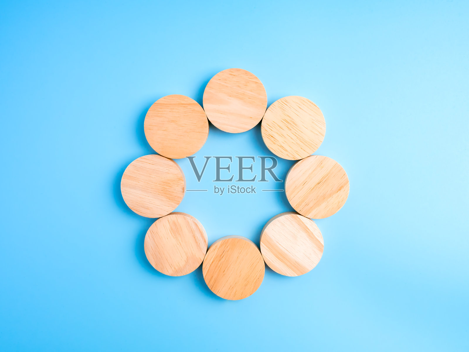 极简生态概念，木质圆形块在蓝色背景上排列成圆形，象征团队合作、过程、信息图模板、可持续性、连接和创意空白空间。照片摄影图片