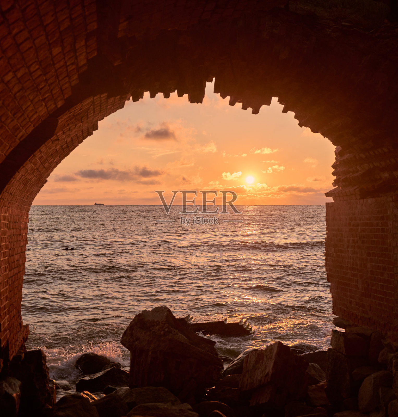 宁静的日落景色透过古老的砖拱门映入海洋照片摄影图片