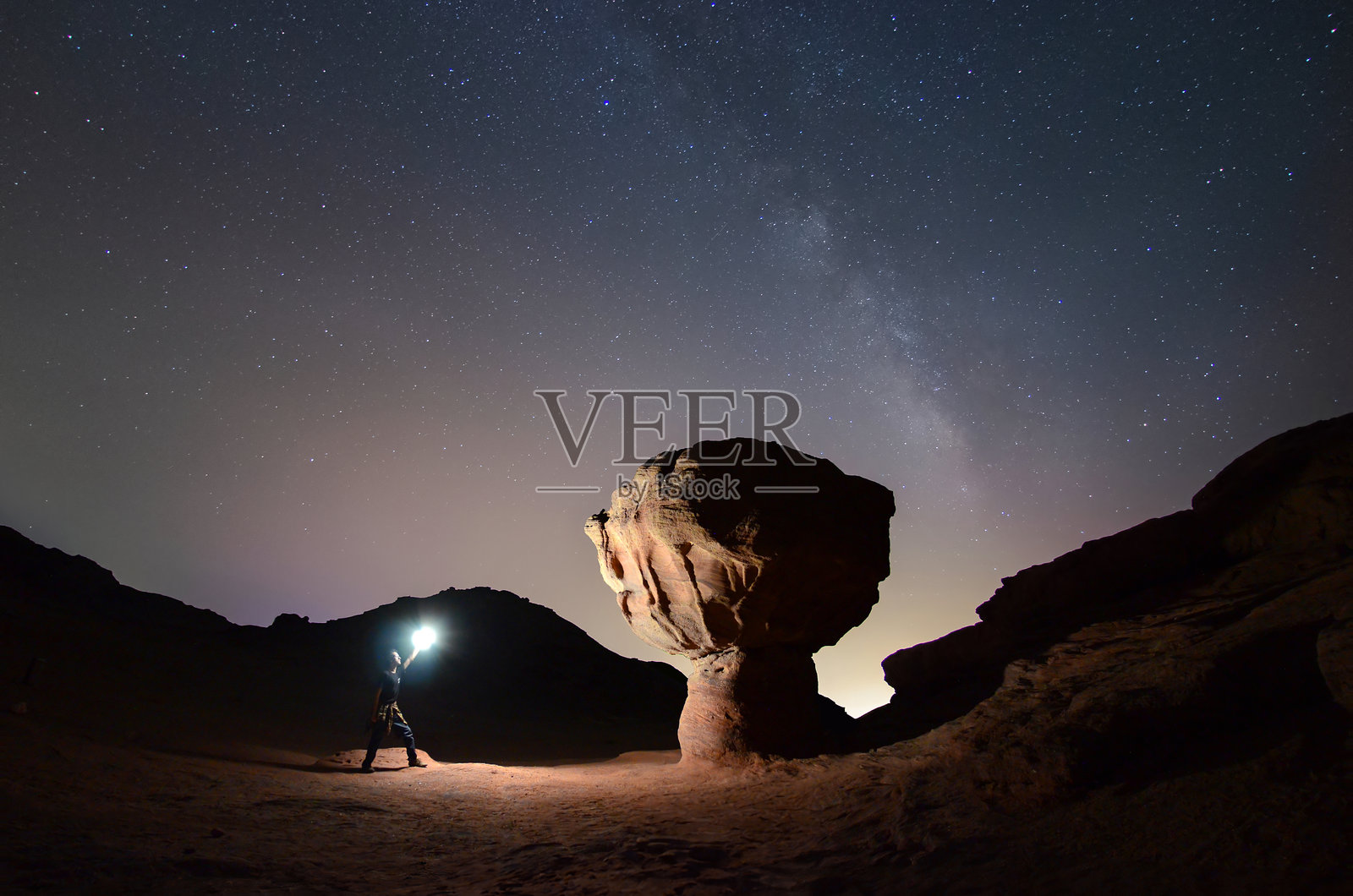 在提姆纳公园，银河夜空下，男子在蘑菇岩附近点亮光源照片摄影图片