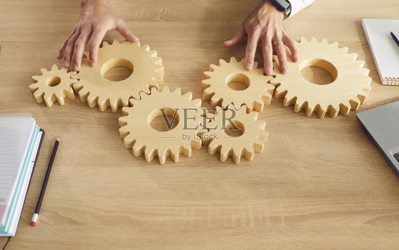 从上方俯视商务人士的手在办公室桌子上连接大型木齿轮。照片摄影图片