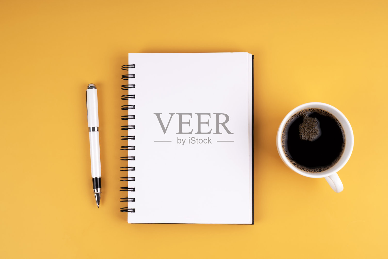 黄色背景上平铺的咖啡杯、笔记本和钢笔照片摄影图片