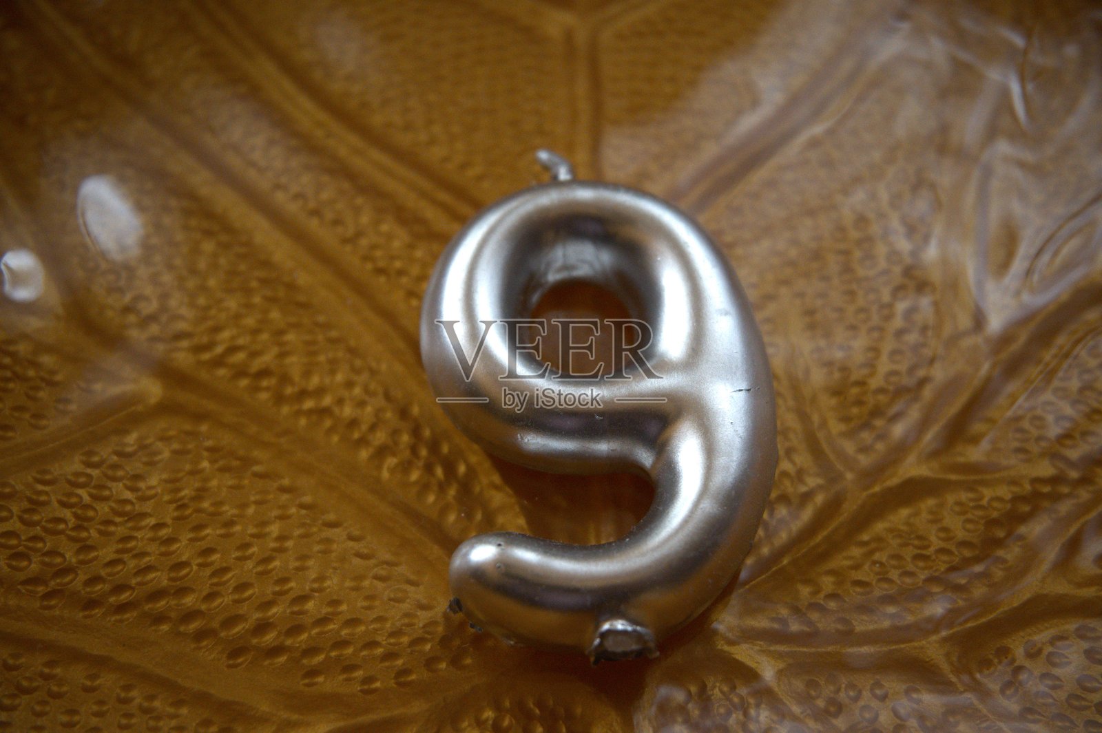 叶子图案盘子上的9号蜡烛特写，留白空间照片摄影图片