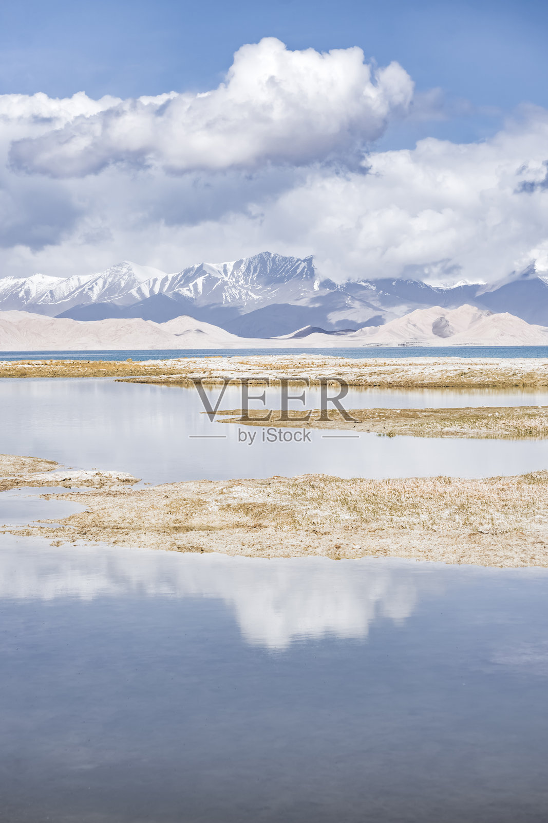 帕米尔山脉中喀拉库尔湖的全景风光，背景是高耸的雪山和云朵，湖泊的晨间全景。照片摄影图片
