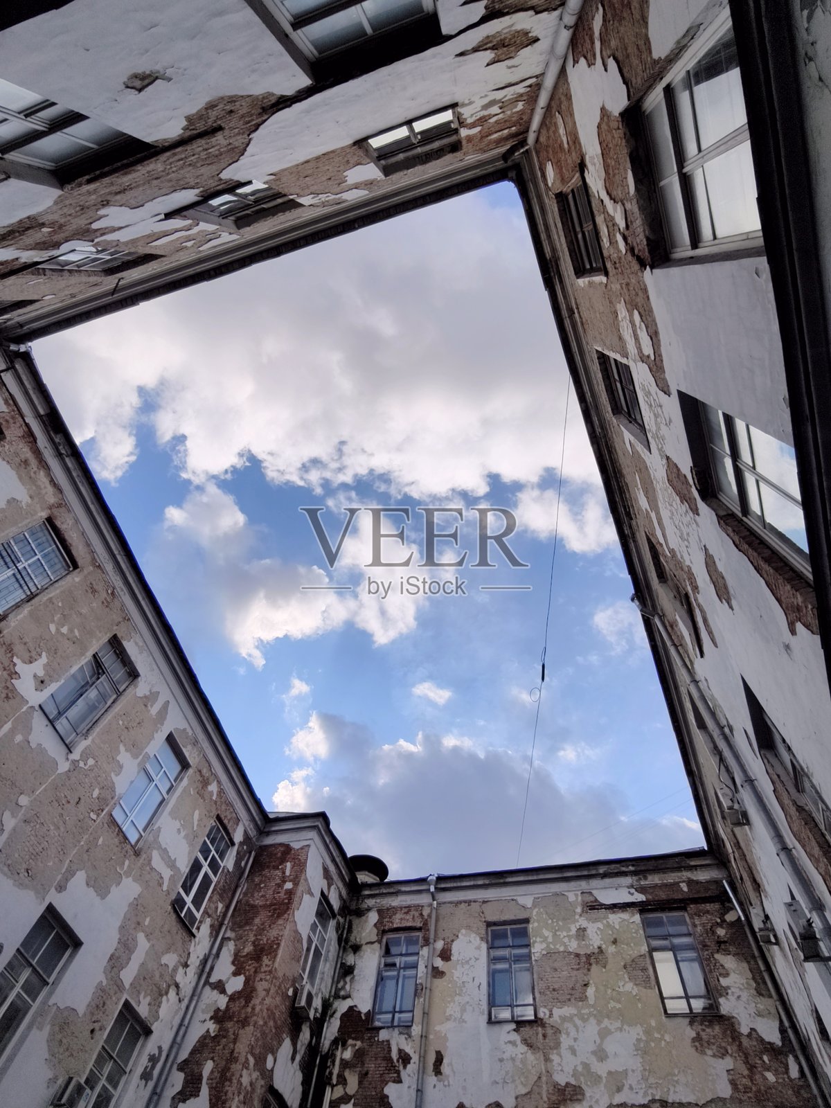 从一个被古老、风化建筑环绕的庭院中仰望，露出一片蓝天和白云，莫斯科，俄罗斯照片摄影图片