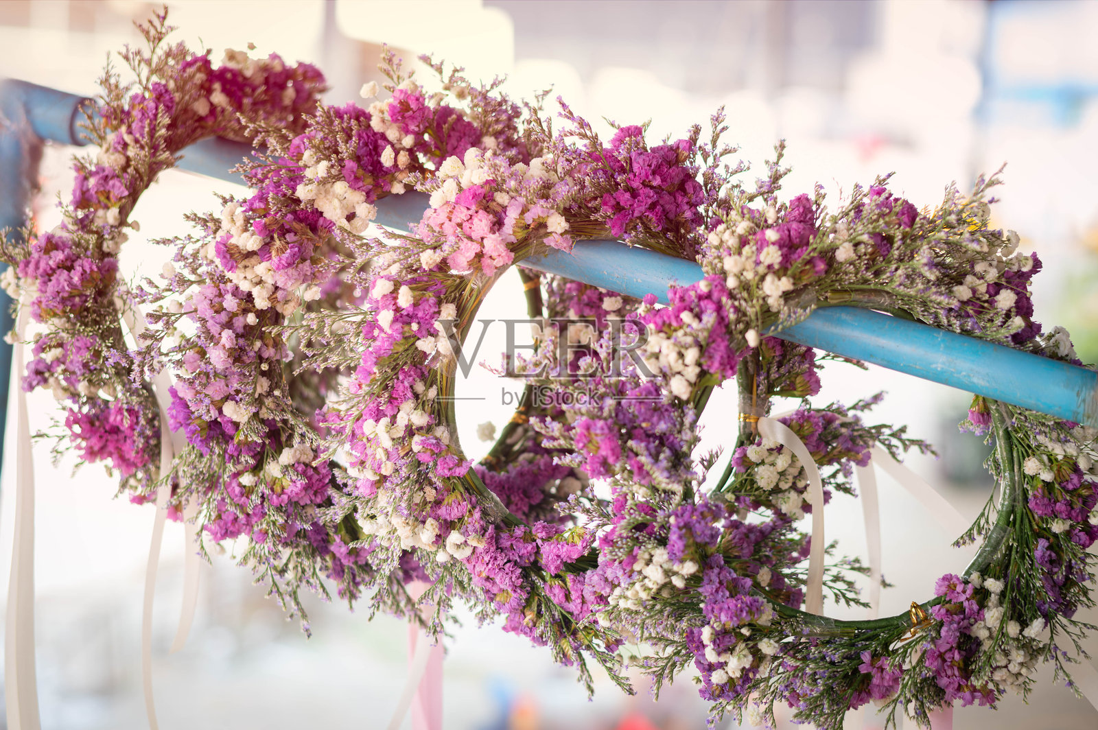 美丽的手工花冠，由干燥的紫色海石竹和白色满天星花制成，整齐悬挂，完美适合婚礼、波西米亚风格活动、花艺设计和春季装饰。照片摄影图片